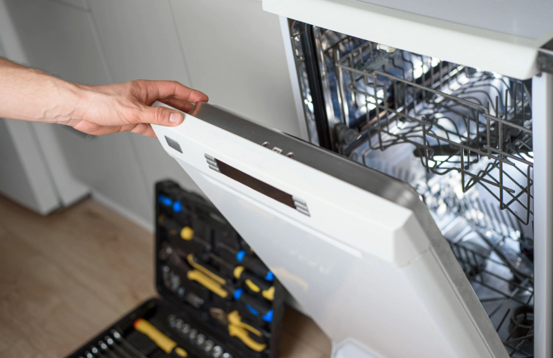 man with repair tools on floor ready to fix dishwasher